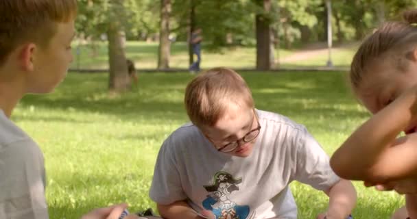 市内公園でカードゲームをしているグループの子供たち ダウン症候群の少年は彼の手にカードを保持し 移動のためのカードを選択します 休暇中のレジャー活動 プラハ ストロモフカ — ストック動画