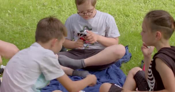 公園で友人とカードゲームをプレイダウン症候群を持つ少年の肖像画 特別なニーズを持つ子供のための包含 プラハ ストロモフカ — ストック動画