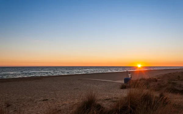 Une personne regardant le coucher du soleil sur la plage — Photo