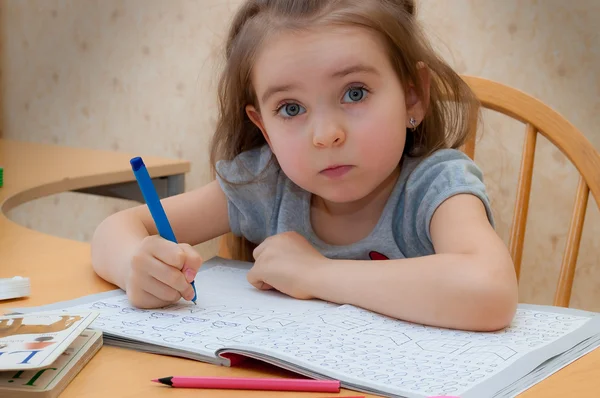 Baby girl sitting writing at the table — Stock Photo, Image