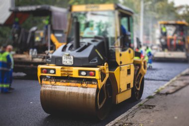 İnşaat ve onarım çalışmaları sırasında asfaltlama, asfalt kaldırım ve kaldırım, asfalt kaldırım makinesi ve buhar silindiri sıkıştırma, inşaat ve onarım çalışmaları, inşaat alanında çalışan işçiler, kiralık araç