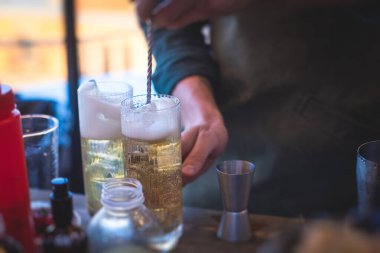 Bir gece kulübünün barında, martinide, votkada ve diğerleri açık havada bile dekore edilmiş ziyafet masasında farklı renkte kokteyller içen güzel bir barmenin önünde.