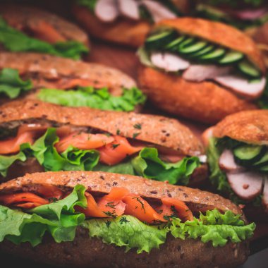 Güzel dekore edilmiş yemek sofrası farklı atıştırmalıklar ve aperatiflerle hazırlanmış sandviç, trianj, kruvasan kulüp denizaltı sandviçi ahşap tabakta, parti ya da kutlama oranıyla.