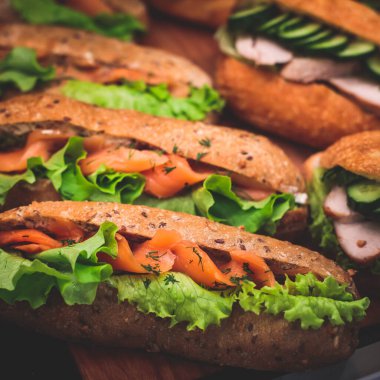 Güzel dekore edilmiş yemek sofrası farklı atıştırmalıklar ve aperatiflerle hazırlanmış sandviç, trianj, kruvasan kulüp denizaltı sandviçi ahşap tabakta, parti ya da kutlama oranıyla.