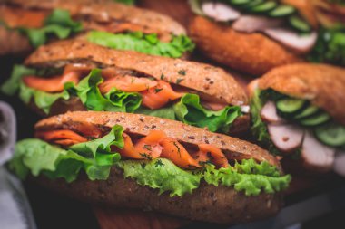 Güzel dekore edilmiş yemek sofrası farklı atıştırmalıklar ve aperatiflerle hazırlanmış sandviç, trianj, kruvasan kulüp denizaltı sandviçi ahşap tabakta, parti ya da kutlama oranıyla.