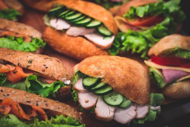 Güzel dekore edilmiş yemek sofrası farklı atıştırmalıklar ve aperatiflerle hazırlanmış sandviç, trianj, kruvasan kulüp denizaltı sandviçi ahşap tabakta, parti ya da kutlama oranıyla.