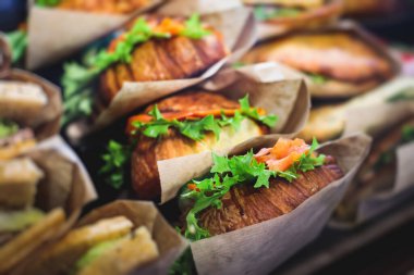 Güzel dekore edilmiş yemek sofrası farklı atıştırmalıklar ve aperatiflerle hazırlanmış sandviç, trianj, kruvasan kulüp denizaltı sandviçi ahşap tabakta, parti ya da kutlama oranıyla.