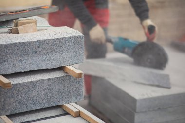 Kesme, kesme ve öğütme işlemi kesme makinesi ile granit beton döşeme, yeni asfalt kaldırım çalışması sırasında dairesel testere ile işçi seramik beton kaplama kesiyor.