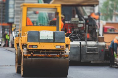 İnşaat ve onarım çalışmaları sırasında asfaltlama, asfalt kaldırım ve kaldırım, asfalt kaldırım makinesi ve buhar silindiri sıkıştırma, inşaat alanında çalışan işçiler, kiralık araç kiralama