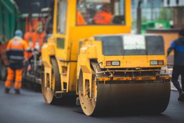 İnşaat ve onarım çalışmaları sırasında asfaltlama, asfalt kaldırım ve kaldırım, asfalt kaldırım makinesi ve buhar silindiri sıkıştırma, inşaat alanında çalışan işçiler, kiralık araç kiralama