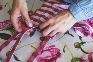 Evde elbise ve pantolonu bağlama, dikiş makinesinin kumaşlarını kapatma, kadın terzinin eliyle terzilik, terzilik, terzilik, giysi ve kumaş dikme süreci. 