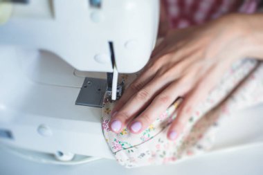Evde elbise ve pantolonu bağlama, dikiş makinesinin kumaşlarını kapatma, kadın terzinin eliyle terzilik, terzilik, terzilik, giysi ve kumaş dikme süreci. 