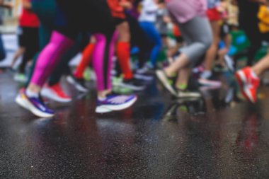 Yağmurda yarışan maraton koşucuları, şehrin asfalt sokaklarında yarı maraton boyunca koşan ayakkabı manzarası, hareket halindeki koşucular, açık hava eğitimi...