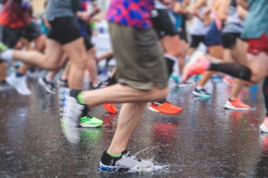 Yağmurda yarışan maraton koşucuları, şehrin asfalt sokaklarında yarı maraton boyunca koşan ayakkabı manzarası, hareket halindeki koşucular, açık hava eğitimi...