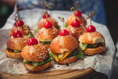 Hamburger mini burgerler ahşap bir masada kağıt üzerinde, güzel dekore edilmiş yemek masası kurumsal bir noel partisinde ya da düğün kutlamasında. 