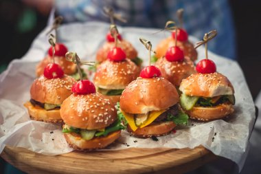 Hamburger mini burgerler ahşap bir masada kağıt üzerinde, güzel dekore edilmiş yemek masası kurumsal bir noel partisinde ya da düğün kutlamasında. 