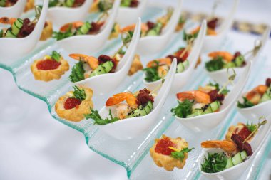 Yemek masası, çeşitli yiyeceklerle süslenmiş güzel bir ziyafet. Kurumsal doğum günü partisi etkinliği ya da düğün kutlaması için aperatifler. Deniz ürünleri, kanepe, canlı şarküteri seti.