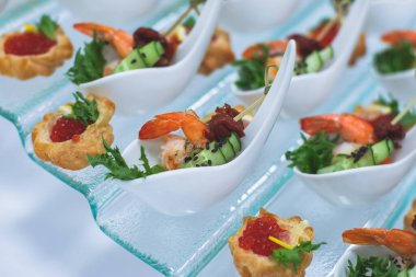 Yemek masası, çeşitli yiyeceklerle süslenmiş güzel bir ziyafet. Kurumsal doğum günü partisi etkinliği ya da düğün kutlaması için aperatifler. Deniz ürünleri, kanepe, canlı şarküteri seti.