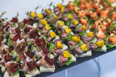 Yemek masası, çeşitli yiyeceklerle süslenmiş güzel bir ziyafet. Kurumsal doğum günü partisi etkinliği ya da düğün kutlaması için aperatifler. Deniz ürünleri, kanepe, canlı şarküteri seti.