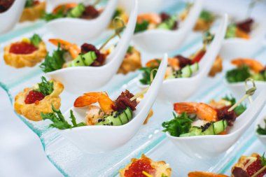 Yemek masası, çeşitli yiyeceklerle süslenmiş güzel bir ziyafet. Kurumsal doğum günü partisi etkinliği ya da düğün kutlaması için aperatifler. Deniz ürünleri, kanepe, canlı şarküteri seti.