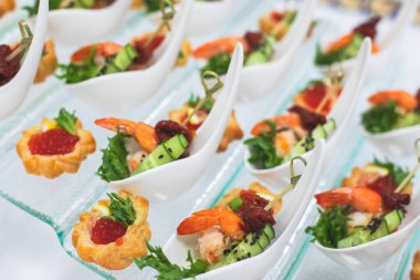 Yemek masası, çeşitli yiyeceklerle süslenmiş güzel bir ziyafet. Kurumsal doğum günü partisi etkinliği ya da düğün kutlaması için aperatifler. Deniz ürünleri, kanepe, canlı şarküteri seti.