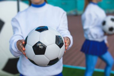 Beyaz mavi üniformalı, arka planda seyirci olan ve futbol maçında performans ve destek veren bir amigo kız grubu.