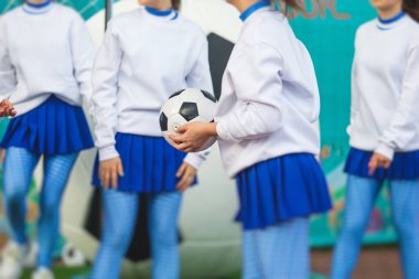 Beyaz mavi üniformalı, arka planda seyirci olan ve futbol maçında performans ve destek veren bir amigo kız grubu.