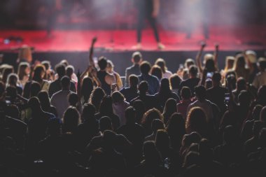 Sahne ışıklarıyla dolu kalabalık bir konser salonu, canlı gösteri performansı, insanların silueti, bir konser sırasında dans pisti.