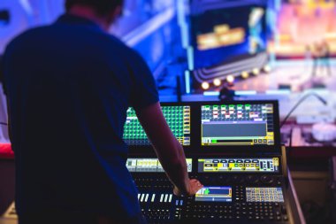 Sahne şovunda canlı konser sırasında konsol işyerinde çalışan ışıklandırma teknisyeninin görüntüsü, ışık karıştırıcı paneli, profesyonel ekipmanlı ses teknisyeni