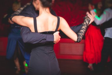 Balo salonunda geleneksel Latin dansı milongası yapan çiftler, kırmızı ve mor ışıklarda tango salsa bachata kizomba dersi, dans festivali