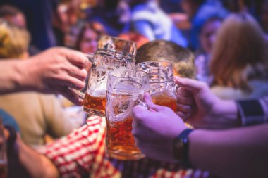 Bira festivali manzarası, bir barda altın renkli bira bardakları, filtresiz Alman buğday birası, insanların neşelenmesi ve hafif bira bardaklarıyla kadeh kaldırması, Oktoberfest manzarası