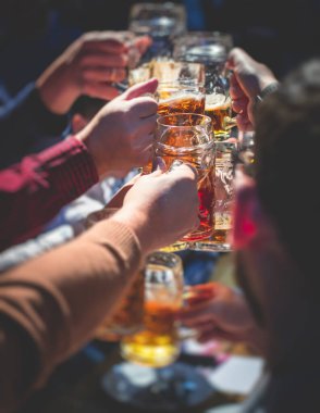 Bira festivali manzarası, bir barda altın renkli bira bardakları, filtresiz Alman buğday birası, insanların neşelenmesi ve hafif bira bardaklarıyla kadeh kaldırması, Oktoberfest manzarası