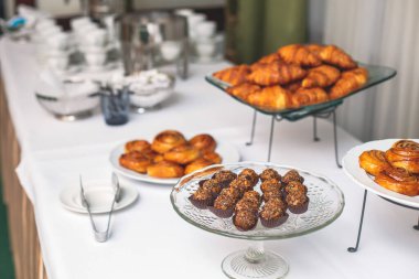 Konferans sırasında otelde kahve molası, çay ve kahve servisi, çeşitli hamur işleri, kruvasan ve kurabiyelerle süslenmiş ziyafet masası.