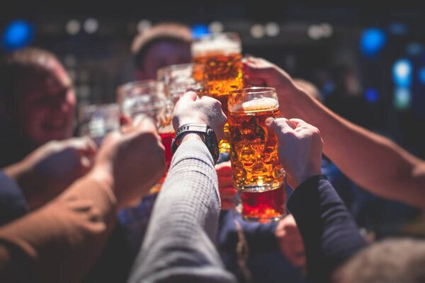 Вид на фестиваль пива, ассортимент пивных бокалов золотого цвета в пабе, немецкое нефильтрованное пшеничное пиво, люди, подбадривающие и тостующие со стаканами светлого пива, вид на Октоберфест