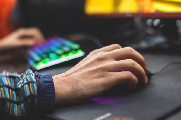 Cyber sport e-sports tournament, team of professional gamers, close-up on gamer's hands on a keyboard and mouse, gamers playing in competitive moba, fps game in a cyber games arena club