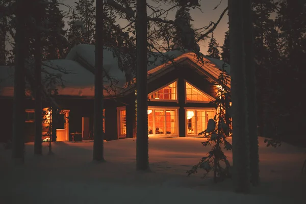 冬のスキーリゾートの近くの雪に覆われた居心地の良い木製のスカンディナヴィアキャビンコテージシャレーハウスの景色とクリスマスライト 夜の写真 — ストック写真
