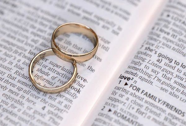 Casal de anéis de casamento de ouro em uma página do dicionário mostrando definição de amor — Fotografia de Stock