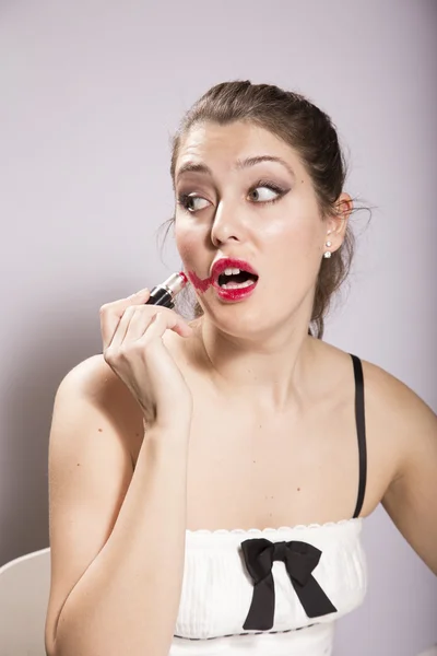 若い女性が彼女の顔に口紅を塗りつける — ストック写真