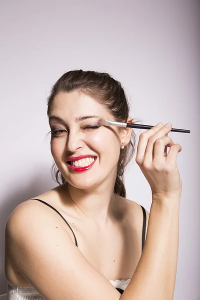 Joven mujer poniendo en sombra de ojos — Foto de Stock