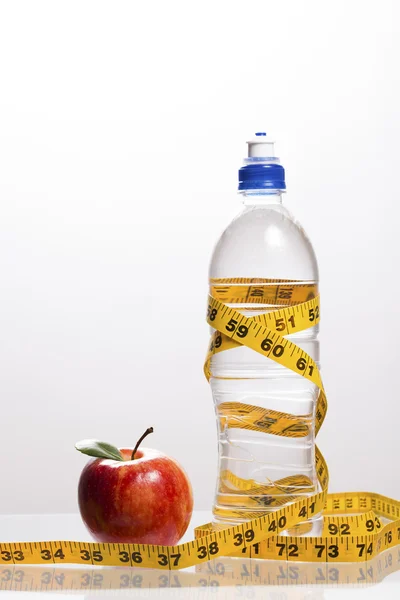 Roter Apfel mit einer Flasche Wasser mit Maßband — Stockfoto