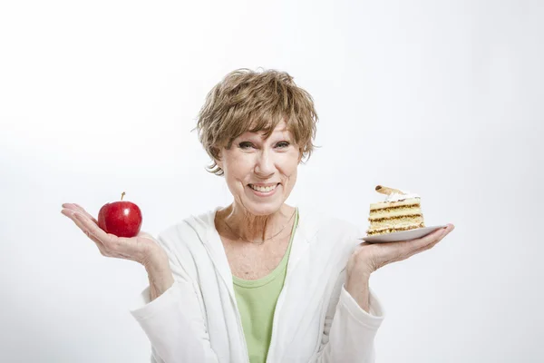 Mature Woman Holding an Apple and Cake — Stock Photo, Image