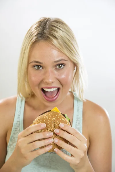 Mladá žena jíst hamburger — Stock fotografie