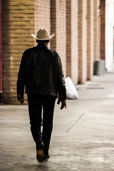 Lonely cowboy walking down the sidewalk — Stock Photo, Image