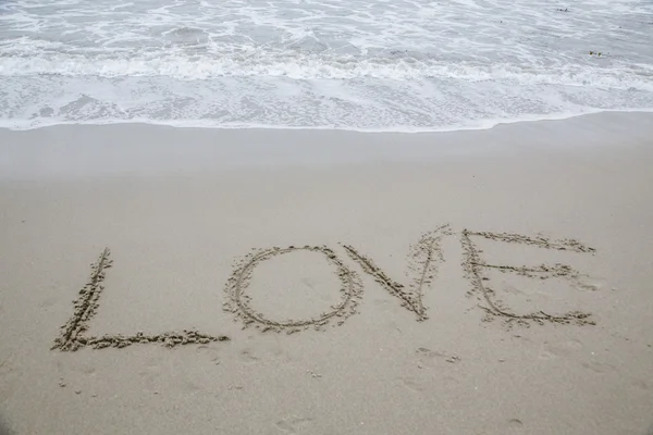 "Love "written in wet sand Стоковое Изображение