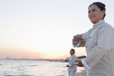 People practicing Taijiquan on the beach at sunset clipart