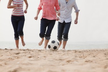 Kumsalda futbol oynayan genç arkadaşlar