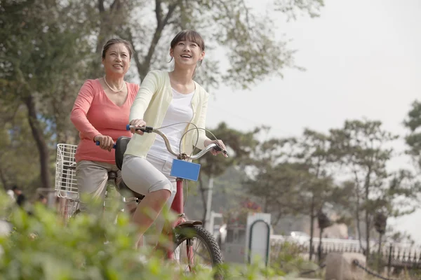 Grandmother and granddaughter riding tandem bicycle — Stock Photo, Image