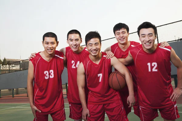 Баскетбольная команда стоя и улыбаясь, портрет — стоковое фото