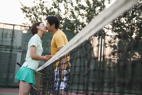 Couple into the tennis net — Stock Photo, Image