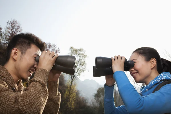 Casal olhando um para o outro através de binóculos — Fotografia de Stock